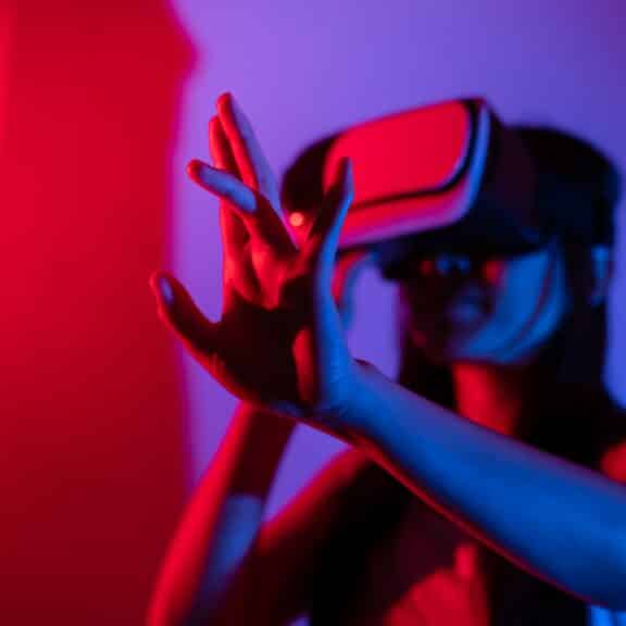 Young woman using glasses of virtual reality on dark background. Smartphone using with VR headset,virtual reality,future technology concept.Asian woman using VR glasses in colorful neon lights.